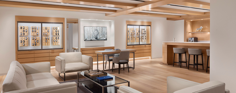 Grand Seiko boutique interior in NYC with white seating, wood accents, and glass display cases.