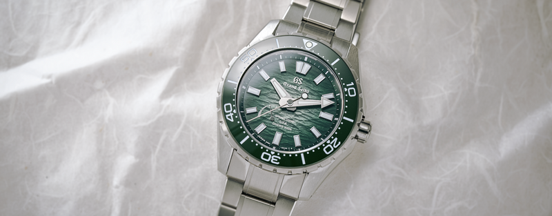 Grand Seiko stainless steel diver watch with green textured dial on light fabric background.