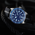 Tudor Pelagos FXD 42mm blue dial dive watch angled on a dark surface with striped fabric strap