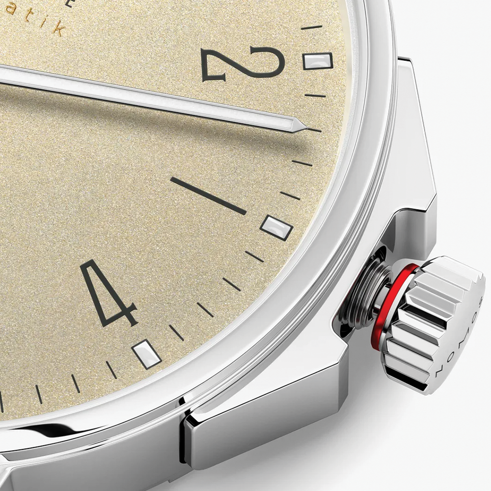 Close up of Ahoi Neomatik Sand beige dial with textured surface and polished steel case.