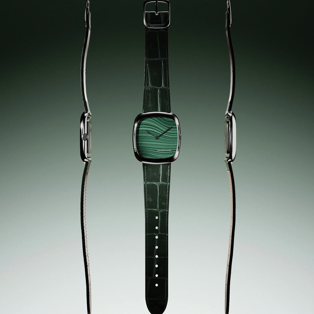Close up of a steel case watch with vivid green malachite dial and green leather strap.