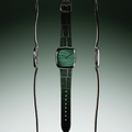 Close up of a steel case watch with vivid green malachite dial and green leather strap.