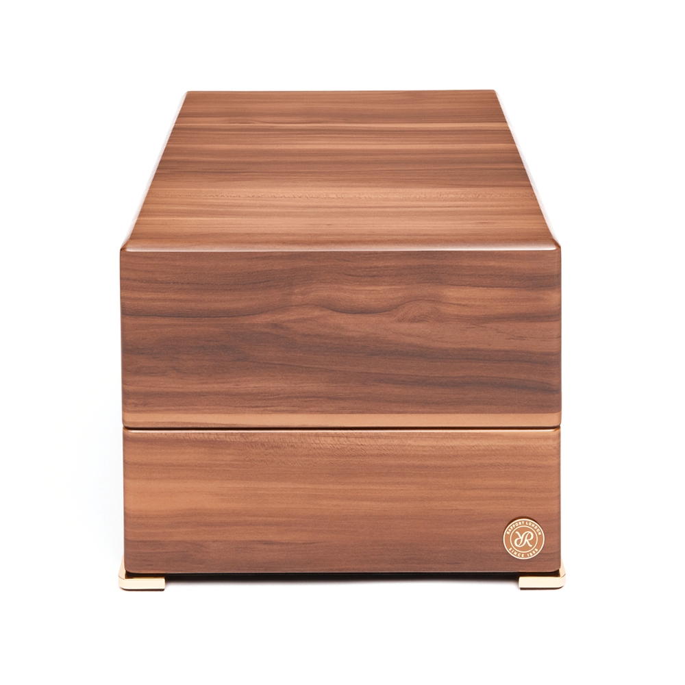 Four watch winder in warm wood finish with gold feet and a small logo badge on the front
