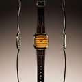 Front and side views of a Dennison tiger eye time only watch in gold case on brown leather strap