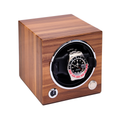 Three-quarter view of the wooden single watch winder with round opening showing a stainless steel watch inside.