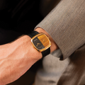 Wrist view of the gold ALD Dual Time watch with tiger eye and marble dial on a black leather strap