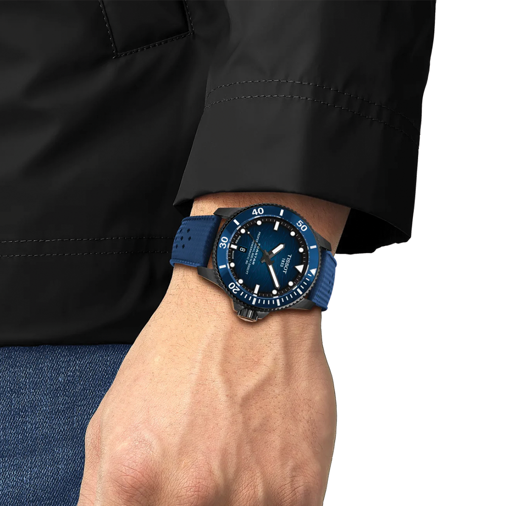 Wrist shot of blue Tissot Seastar 2000 diver watch on a blue rubber strap worn with a black jacket