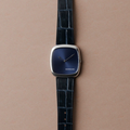 Close-up of blue sunray dial watch in steel with a dark blue leather strap.