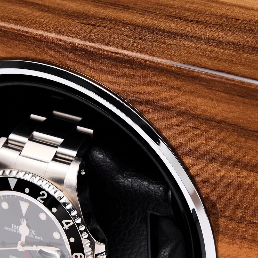 Close up of a stainless steel watch partially visible inside a wood finished watch winder