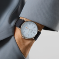 Wrist shot of Ahoi Neomatik Sky watch with a light blue dial steel case and dark blue fabric strap