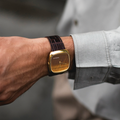 Wrist view of a gold case tiger eye watch on a brown leather strap