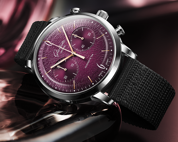 Luxury watch with a purple face and black strap on a reflective surface