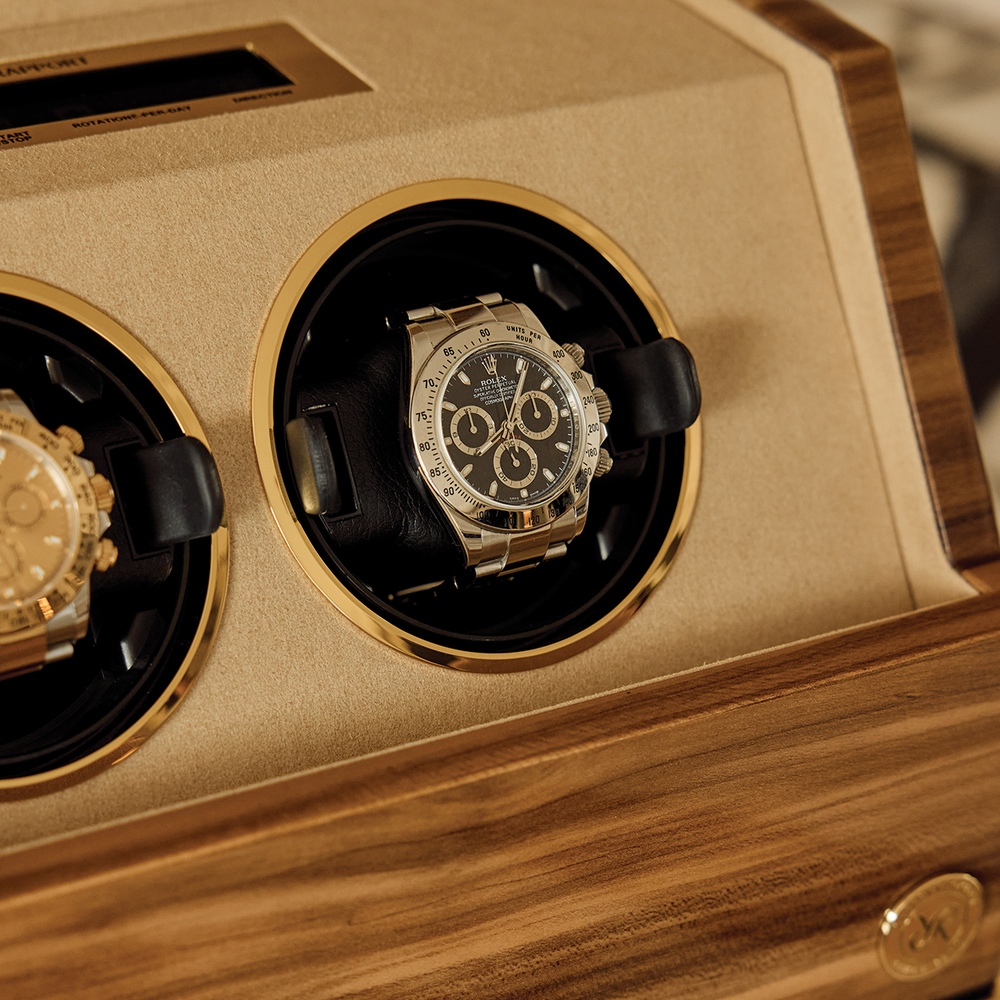 Close-up of the right circular slot with a black dial watch secured in the gold-rimmed holder inside the wooden winder