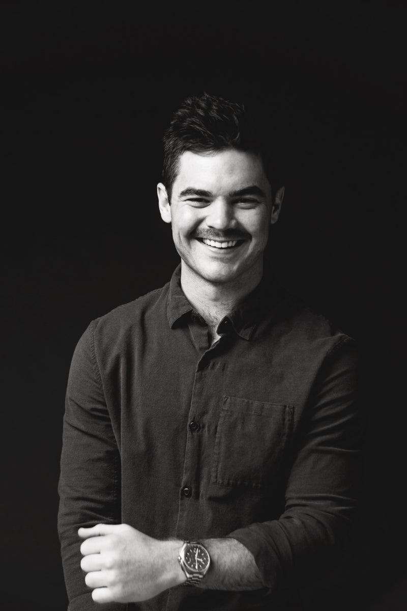 Black and white portrait of a man wearing a watch on a dark background