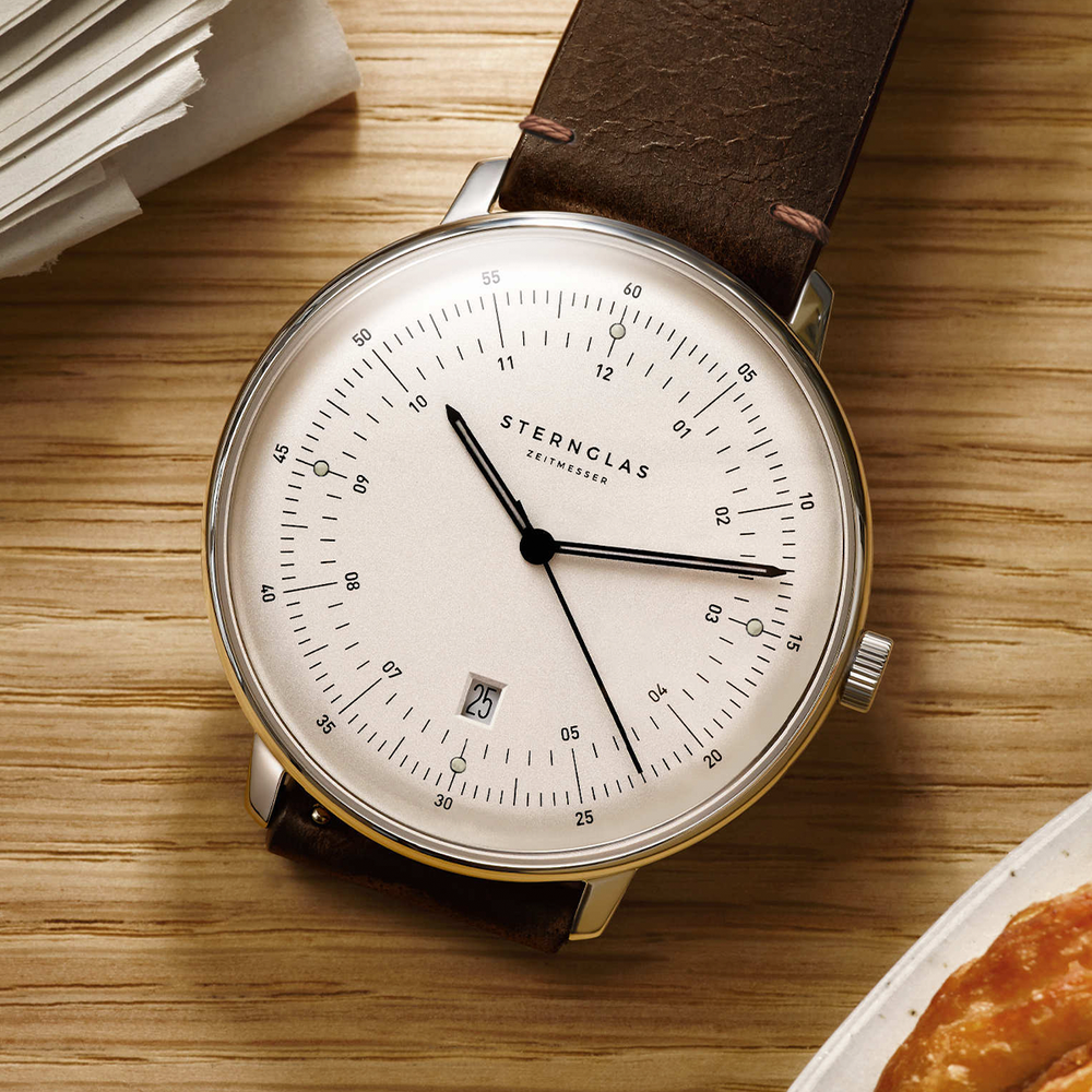 Hamburg Quartz 42mm watch with white dial on brown leather strap resting on a wooden surface