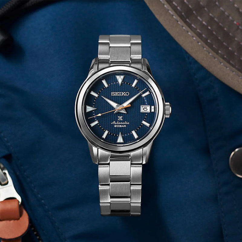 Seiko SPB249 Prospex Land blue dial wristwatch on a stainless steel bracelet against blue fabric.