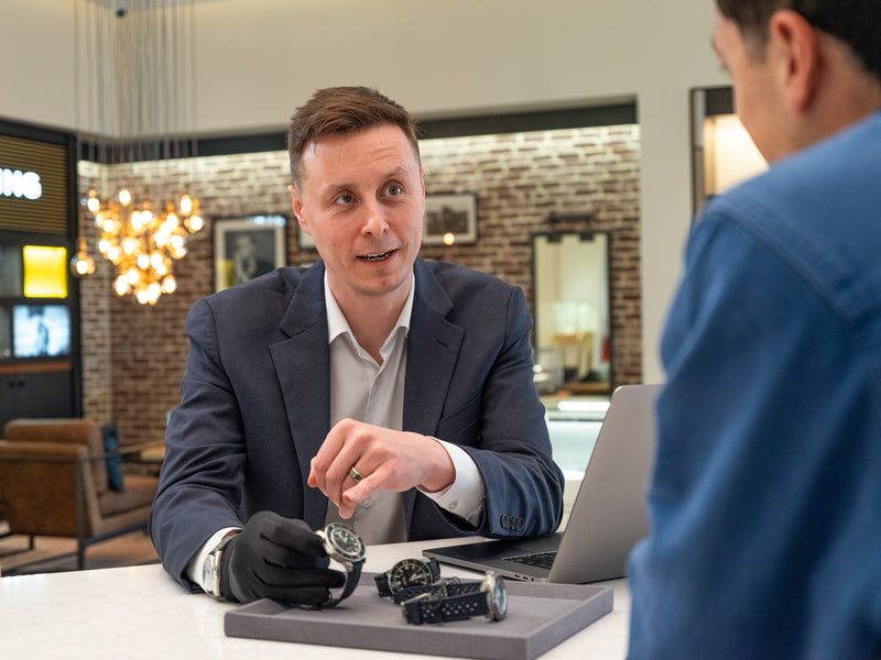 Man in suit pointing at a watch