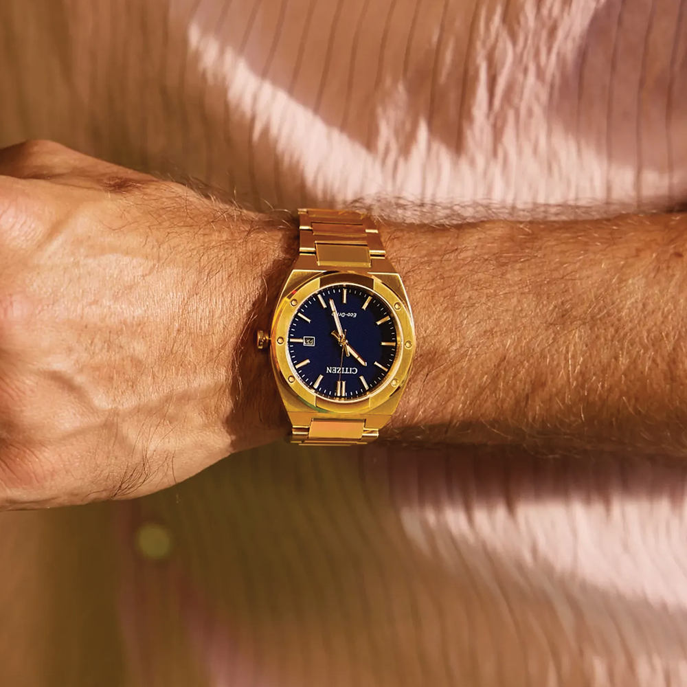 Gold-tone Sport Luxury 40mm watch worn on the wrist, blue dial visible