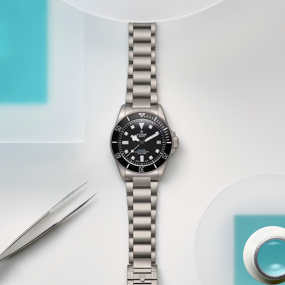 Pelagos Ultra Titanium 43mm watch with black dial on titanium bracelet against a pale background.