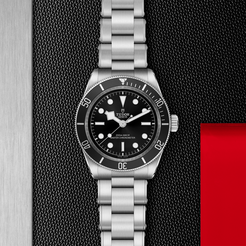 Black Bay 41mm Tudor diver watch with black dial on stainless steel bracelet against a textured backdrop